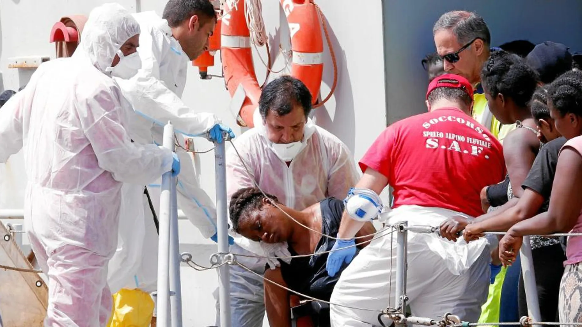 Personal médico de la Marina italiana socorre ayer a una mujer a su llegada al puerto italiano de Reggio Calabria
