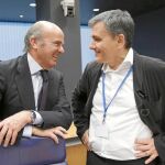 Luis de Guindos, con Euclides Tsakalotos, ayer, en el Eurogrupo