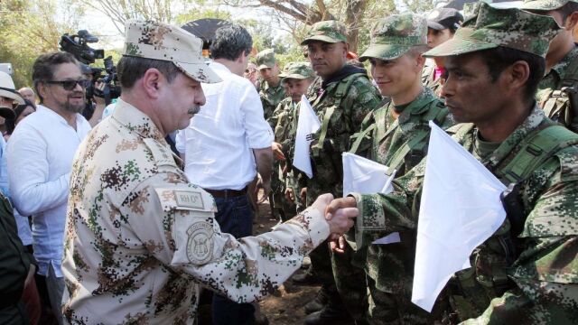 El jefe guerrillero de las Farc, Luciano Marín Arango, alias "Iván Márquez"(c), el comandante del Comando Estratégico de Transición del Ejército colombiano, general Javier Florez (c), y el Alto Comisionado para la Paz colombiano, Sergio Jaramillo (espalda), saludan a los guerrilleros