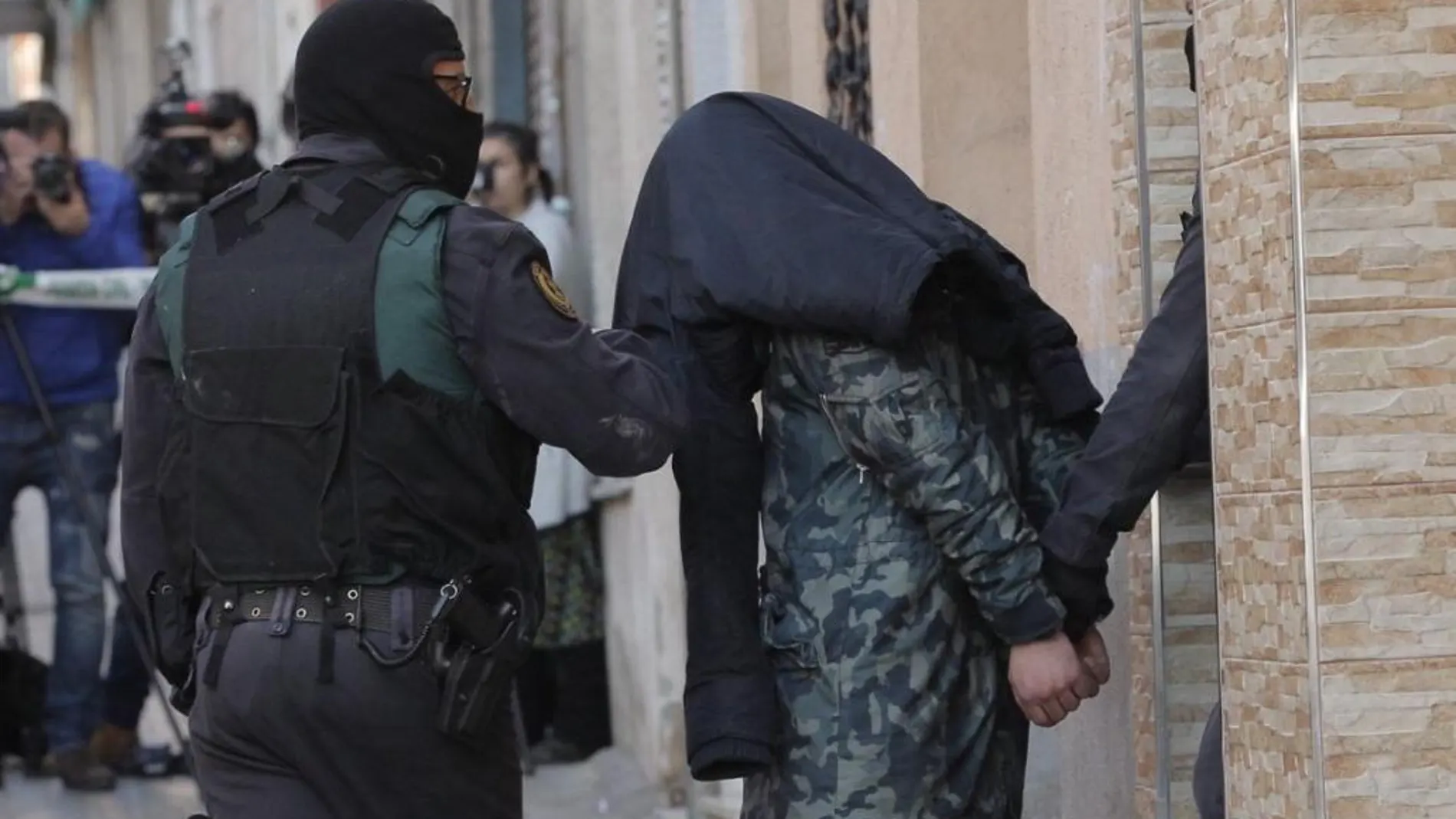 Agentes de la Guardia Civil custodian a uno de los dos ciudadanos marroquíes detenidos ayer en Badalona (Barcelona), acusados de realizar actividades de captación, adoctrinamiento y financiación de yihadistas