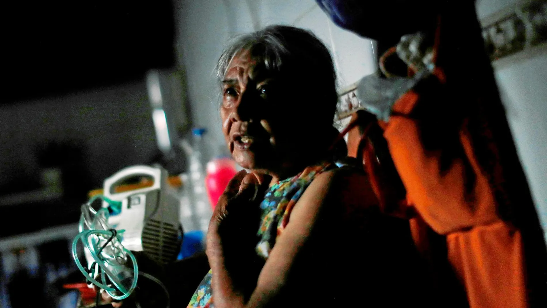 Una anciana sentada junto a su máquina nebulizadora apagada en el barrio de Caracas / Reuters