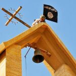 Un miembro del EI sujeta la bandera mientras derriba una cruz en Mosul