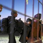 Varios refugiados cargan con sus pertenencias tras abandonar el campo de refugiados de Gevgelija, Macedonia, camino a la estación de autobuses para dirigirse a Serbia