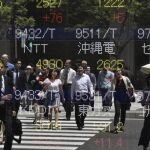 Peatones reflejados en los indicadores de mercado en Tokio