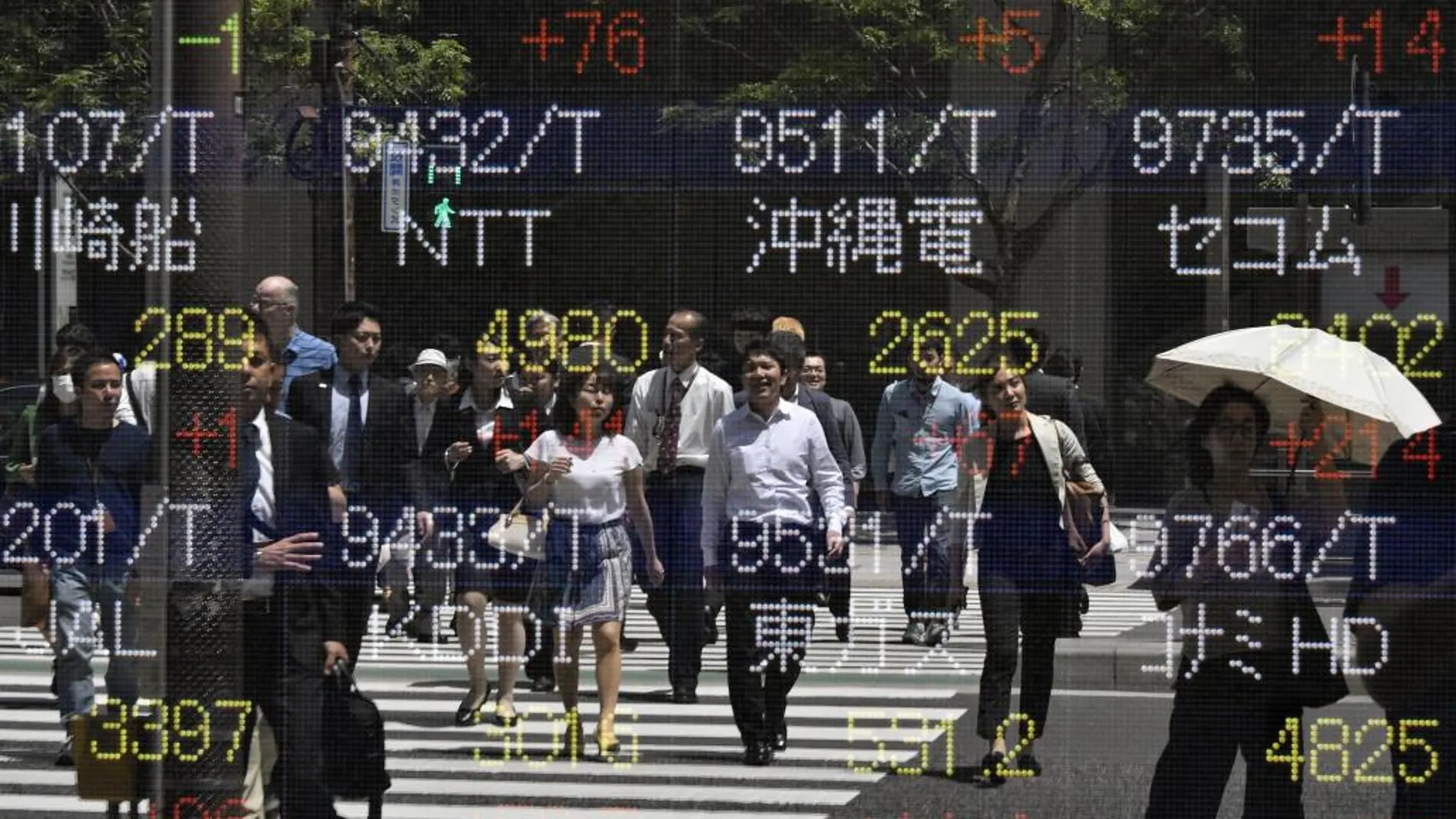 Peatones reflejados en los indicadores de mercado en Tokio
