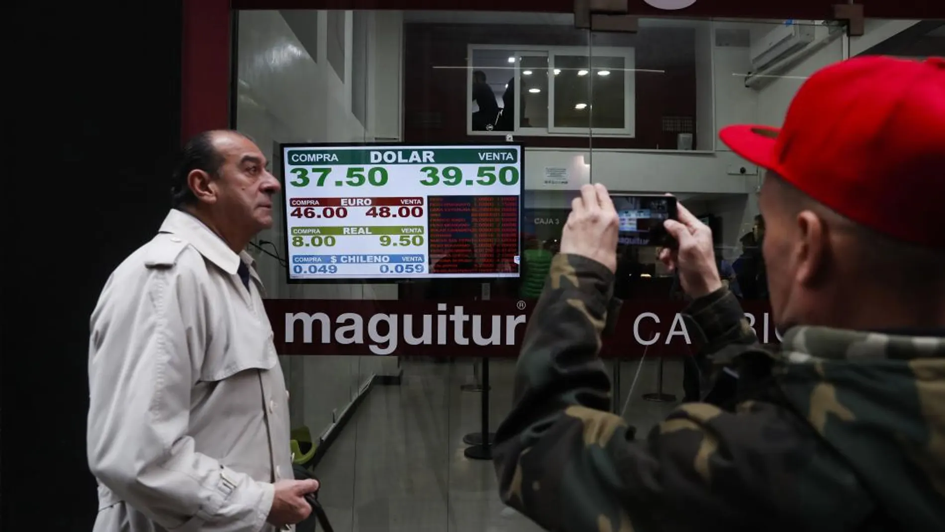 Transeúntes observan y fotografían los paneles de las casas de cambio en el centro de Buenos Aires / Efe