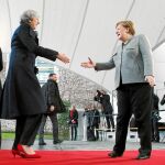 Atrapada en la limusina La canciller Angela Merkel saluda a la «premier» Theresa May, que se había quedado atrapada en su coche oficial