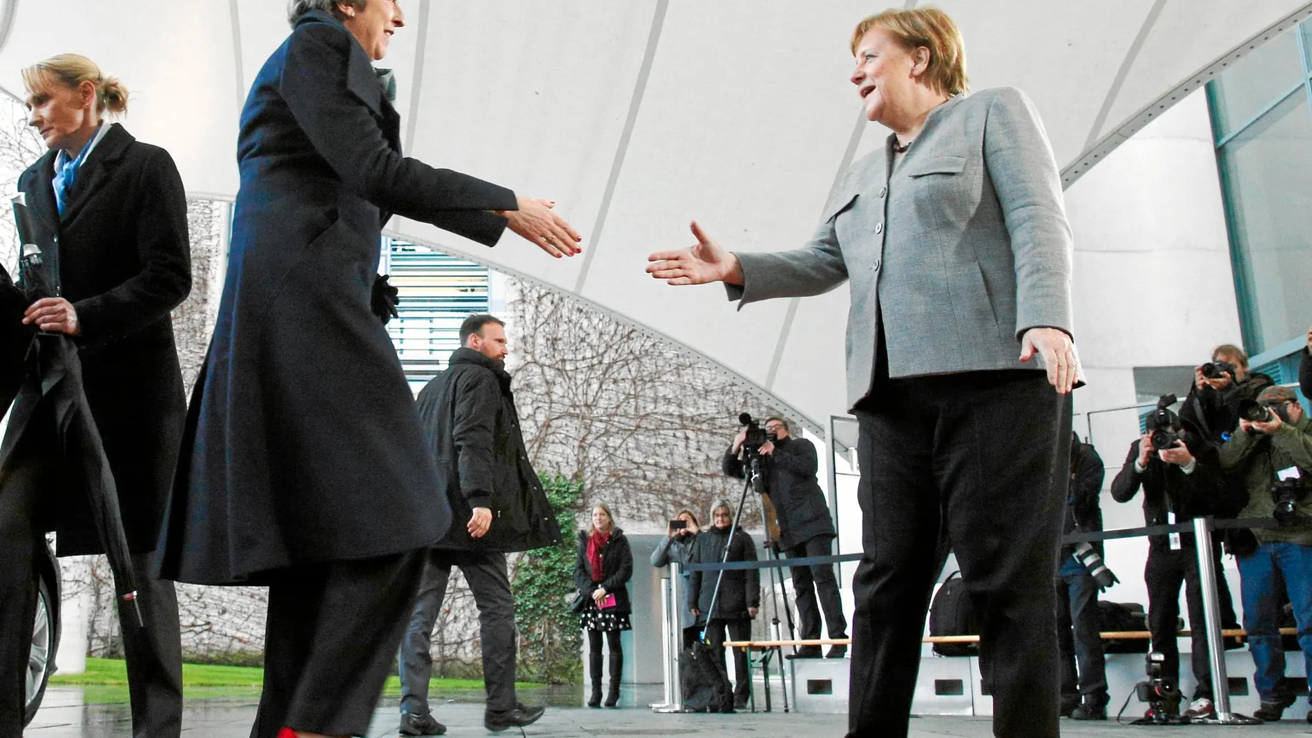 Atrapada en la limusina La canciller Angela Merkel saluda a la «premier» Theresa May, que se había quedado atrapada en su coche oficial