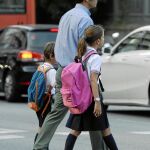 En la imagen, un padre acompañando a sus dos hijos a la escuela