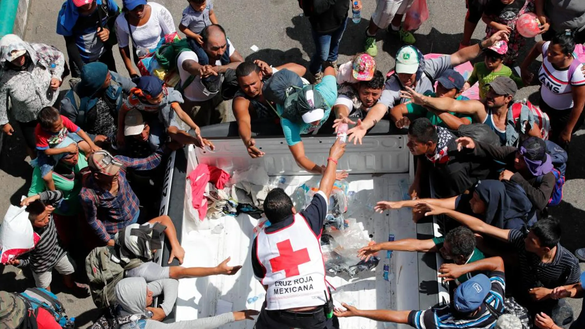 Personal de la Cruz Roja entrega agua a migrantes hondureños que continúan recorriendo otro tramo del territorio mexicano rumbo a su objetivo principal, Estados Unidos