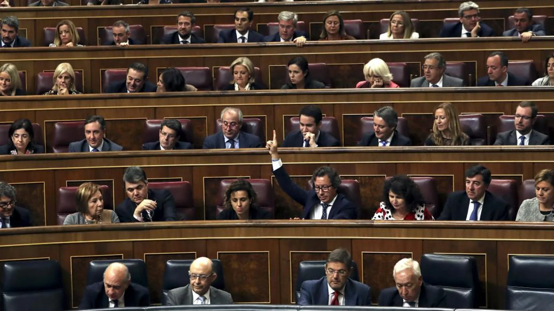 El diputado del PP Carlos Floriano marca el sentido del voto a sus compañeros de partido, durante el pleno que se ha celebrado esta tarde en el Congreso de los Diputados
