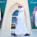 Un hombre habla por teléfono mientras camina por las calles de Riad y pasa ante dos posters del rey Salman y su hijo el príncipe Mohamed, los ciudadanos aprueban las medidas anticorrupción