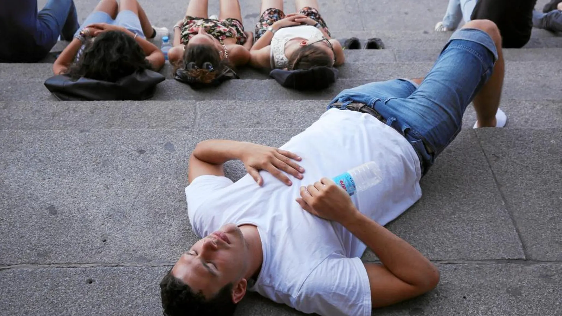 Varios turistas sofocados por las altas temperaturas descansan en las escaleras de la Catedral de la Almudena