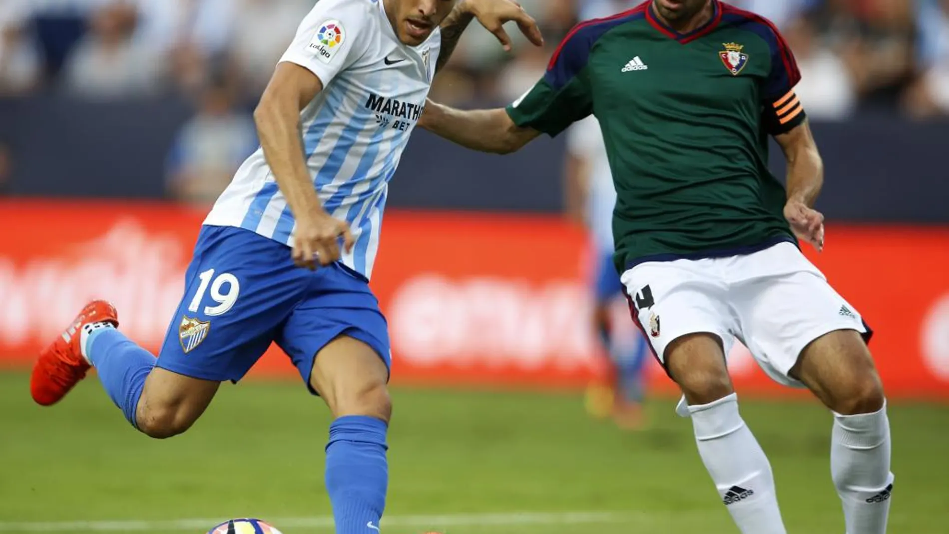El defensa del Club Atlético Osasuna M. Flaño (d) lucha el balón con el delantero del Málaga CF, Sandro (i)