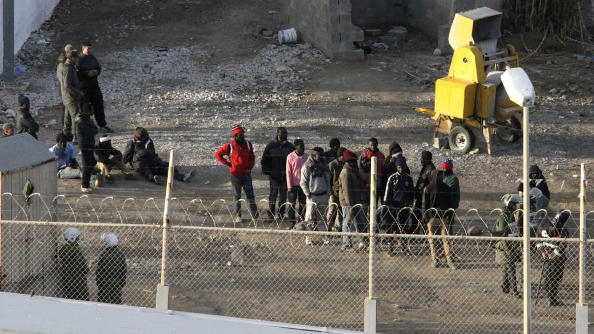 Inmigrantes subsaharianos rodeados por la Policía marroquí, en el perímetro fronterizo de Ceuta