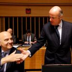 El ministro de Economía español, Luis de Guindos (dcha), saluda al comisario europeo de Asuntos Económicos y Financieros, Pierre Moscovici,
