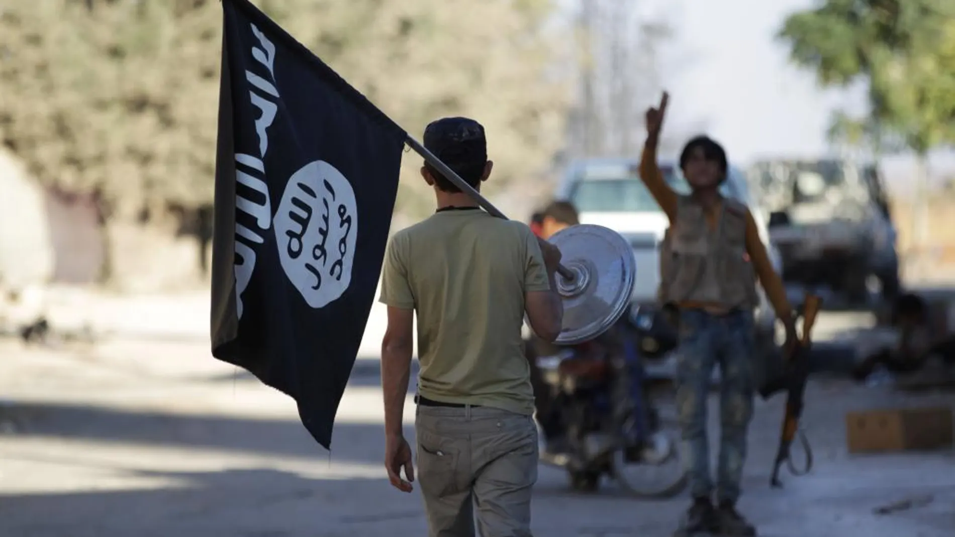 Un soldado de una de las facciones rebeldes porta una bandera capturada al Estado Islámico en el entorno de Dabiq.