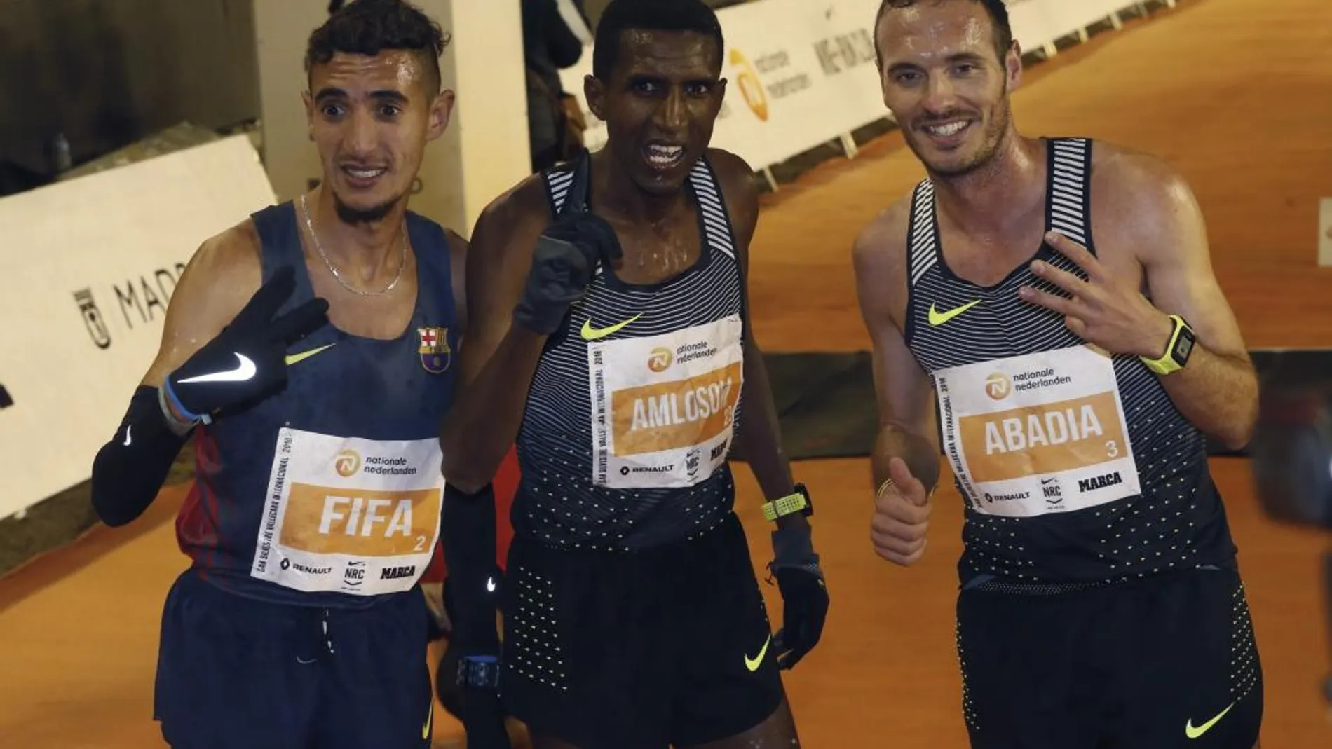 Neguse Amloson, c, ganador de la carrera internacional de la San Silvestre Vallecana acompañado del español Ilias Fifam,iz, segundo clasifiacado y Antonio Abadía,tercero, posan tras cruzar la meta de la prueba en el estadio de Vallecas