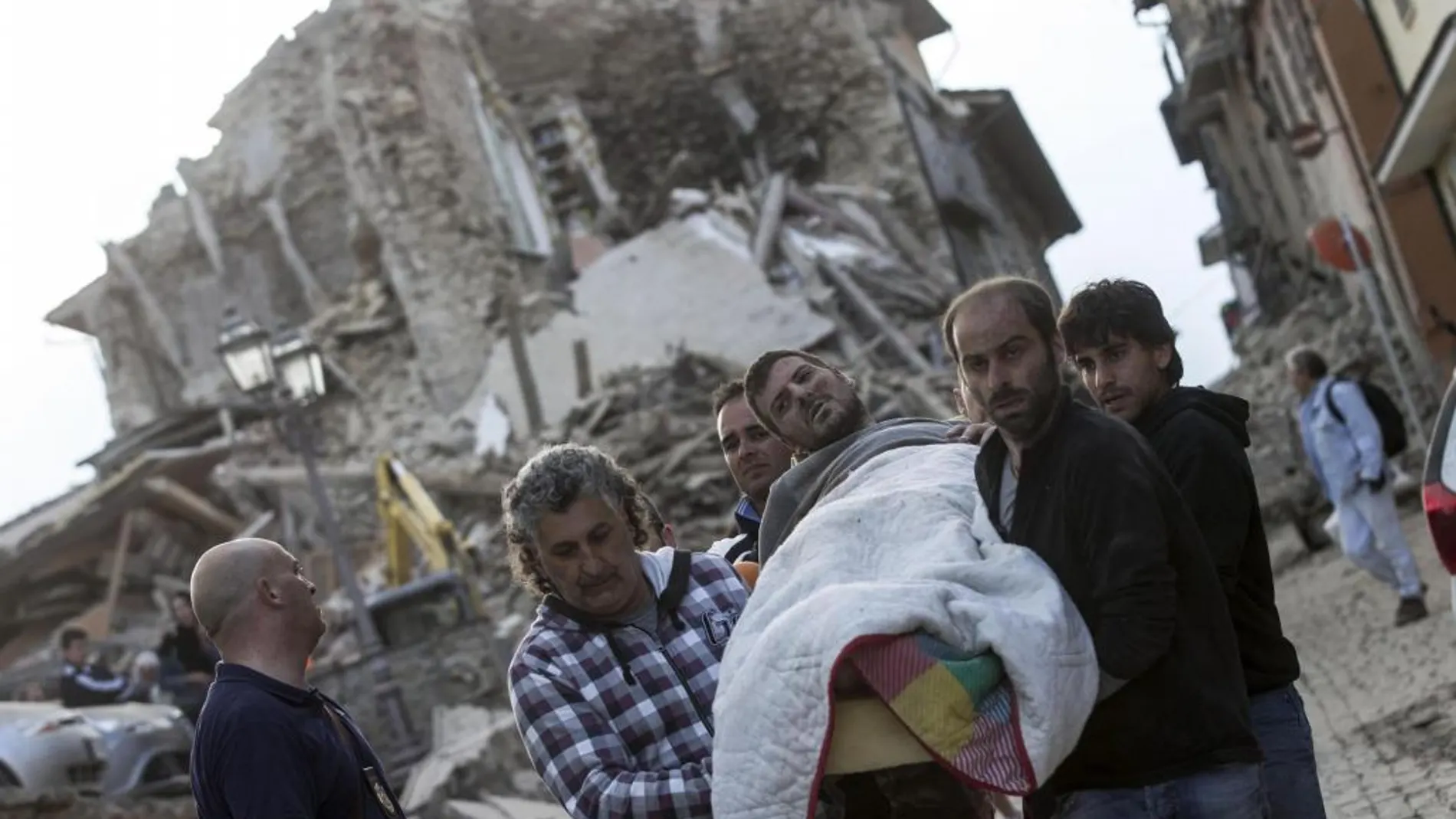 Un hombre herido (c) es rescatado por los equipos de emergencia en Amatrice.