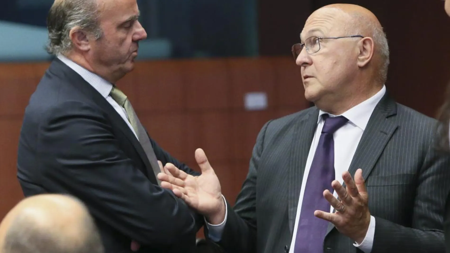 Luis de Guindos conversa con el ministro de Finanzas francés, Michel Sapin (d) durante la reunión del Eurogrupo del pasado 11 de julio