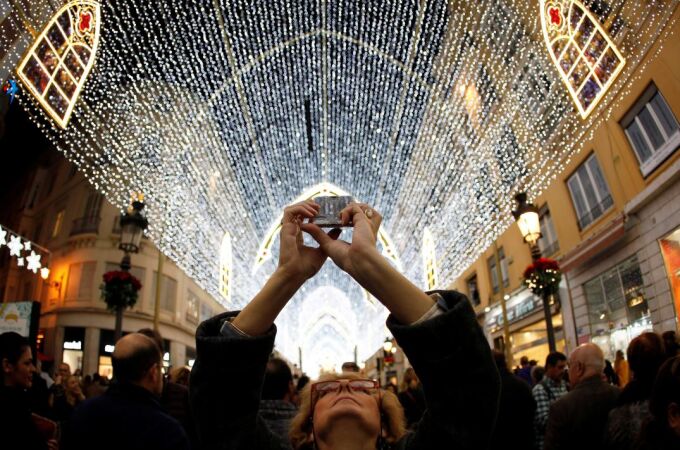 Una mujer fotografía con su móvil la iluminación navideña en Málaga