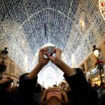 Una mujer fotografía con su móvil la iluminación navideña en Málaga