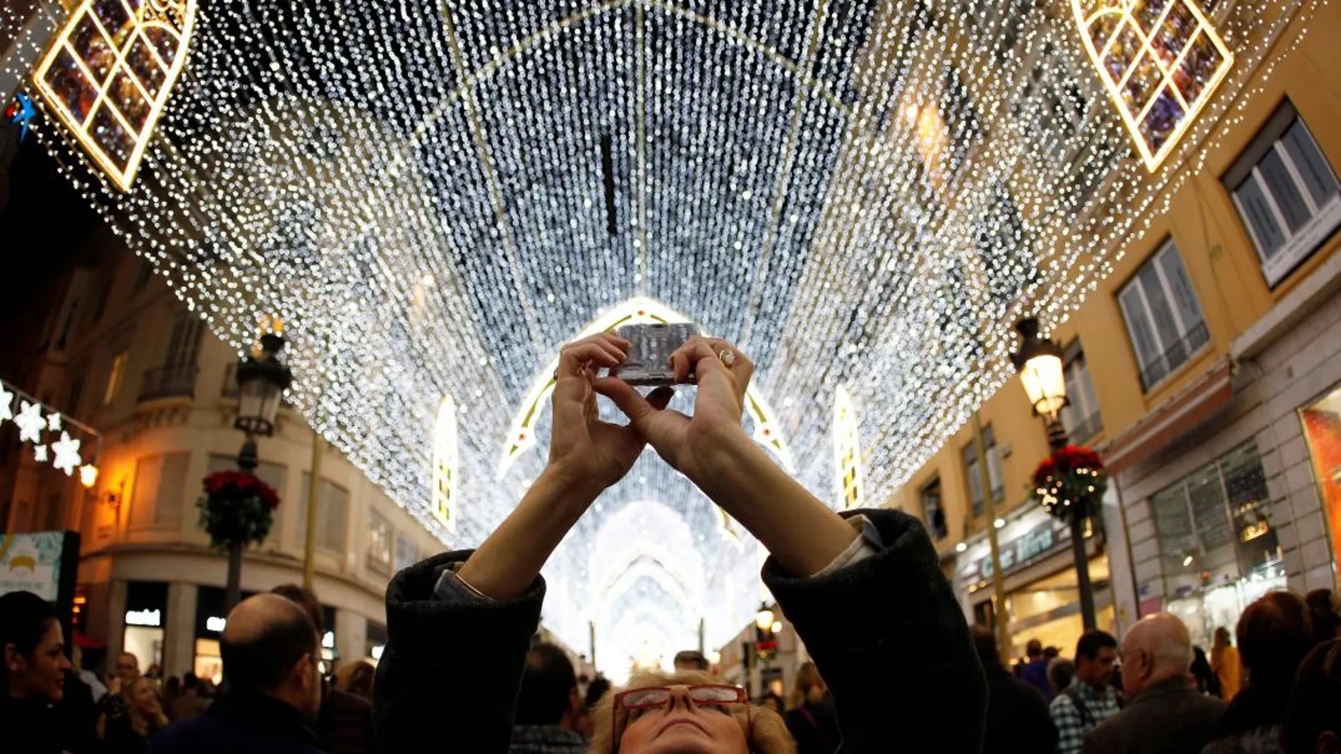 Una mujer fotografía con su móvil la iluminación navideña en Málaga