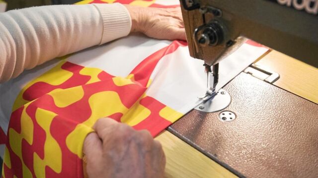 Una mujer cose una de las banderas que durante estos días se confeccionan en la empresa catalana Banderas Aap