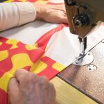 Una mujer cose una de las banderas que durante estos días se confeccionan en la empresa catalana Banderas Aap