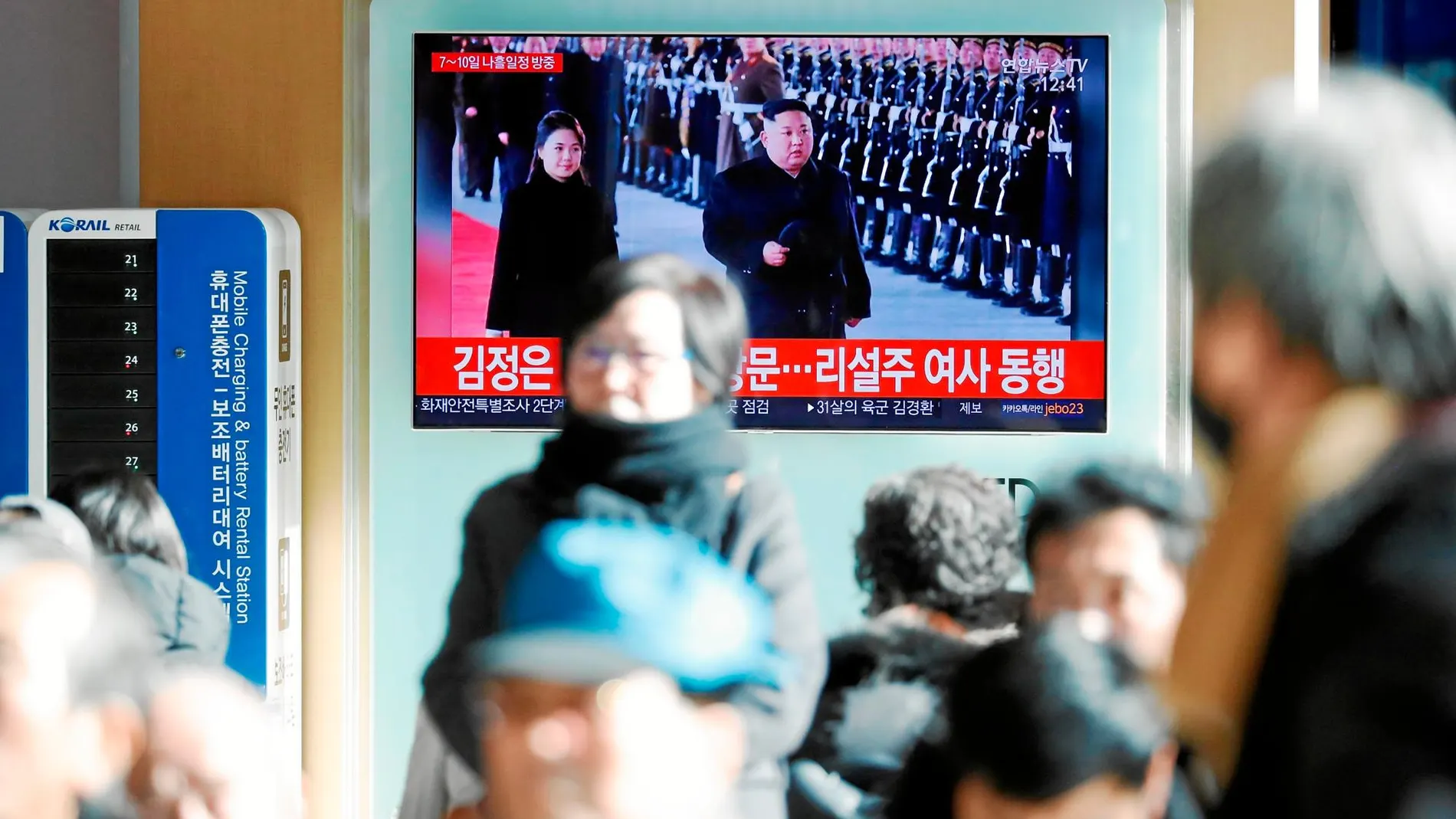 Varios peatones siguen la visita de Kim Jong Un a China en una pantalla de una céntrica calle de Seúl, capital de Corea del Sur