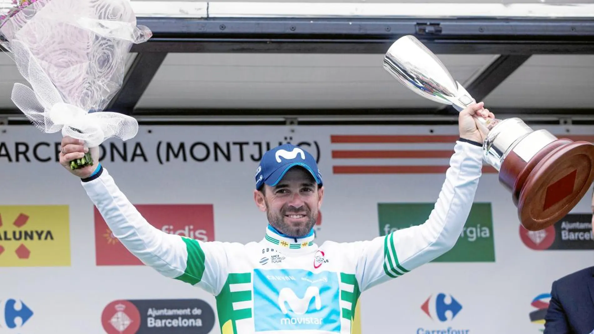 Valverde, vestido con el maillot de líder de la Volta, el trofeo de ganador en la izquierda y el ramo de flores en la derecha