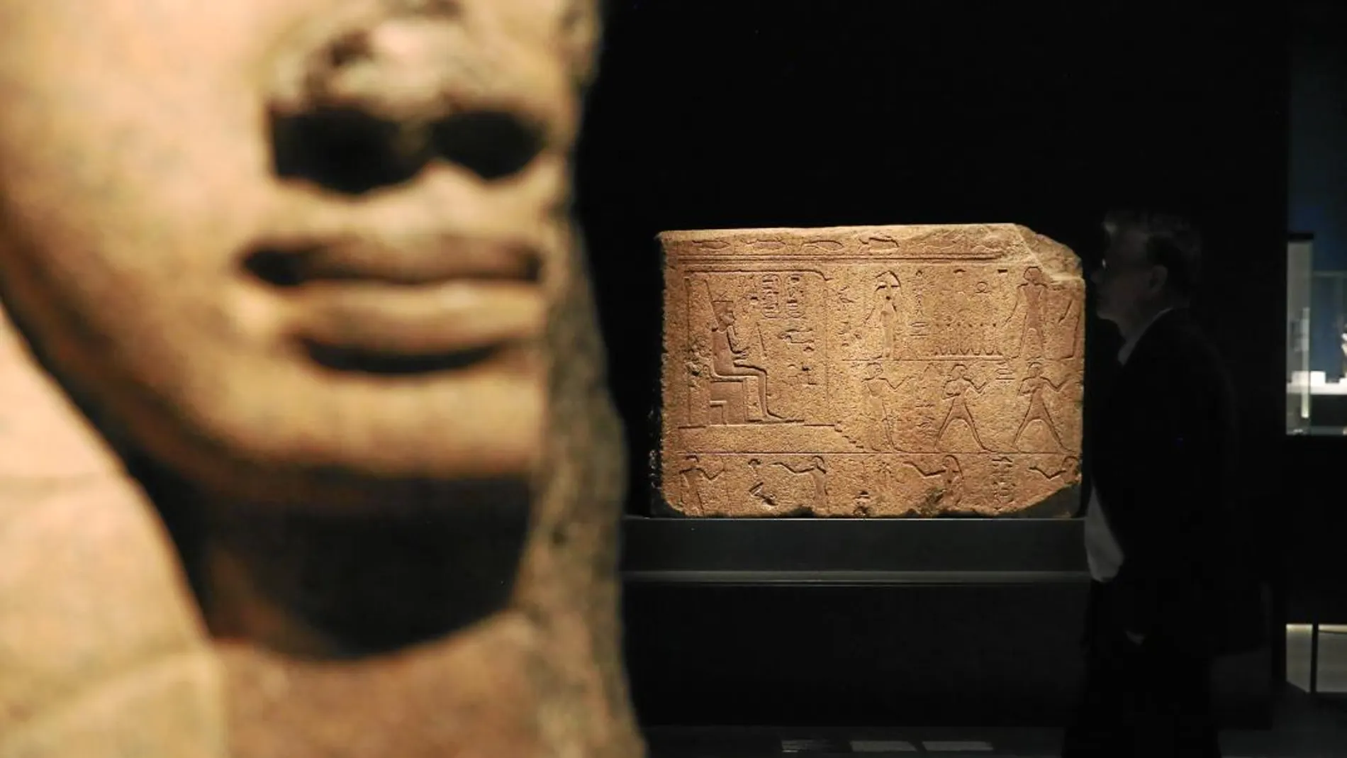 En primer plano, un capitel con la forma de la diosa Hathor procedente del templo de Bastet. Al fondo, un relieve del faraón Osorkon II que formó parte de un portal también del templo de Bastet