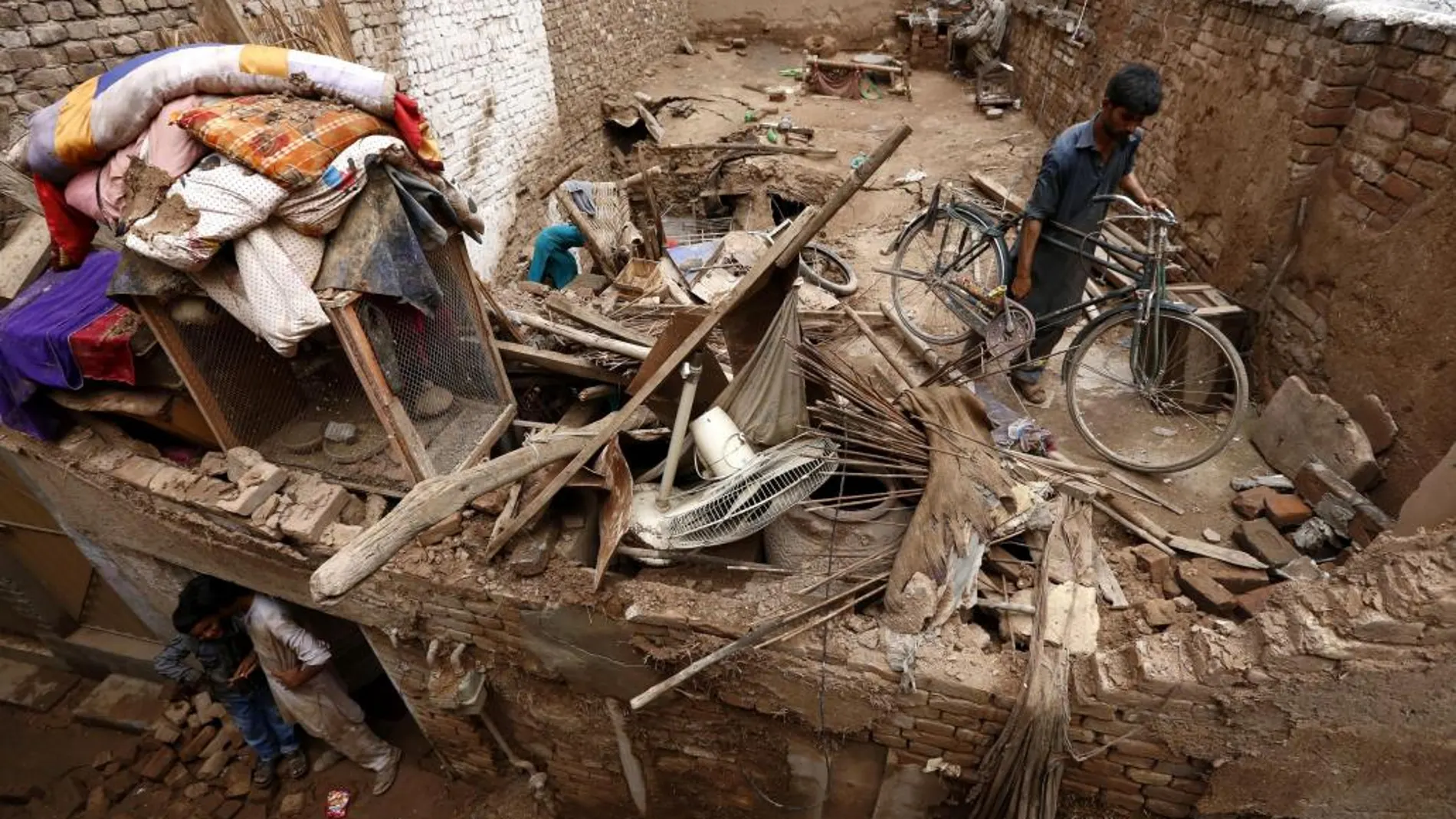 Un hombre intenta recuperar algunas de sus pertenencias tras las fuertes lluvias en Peshawar