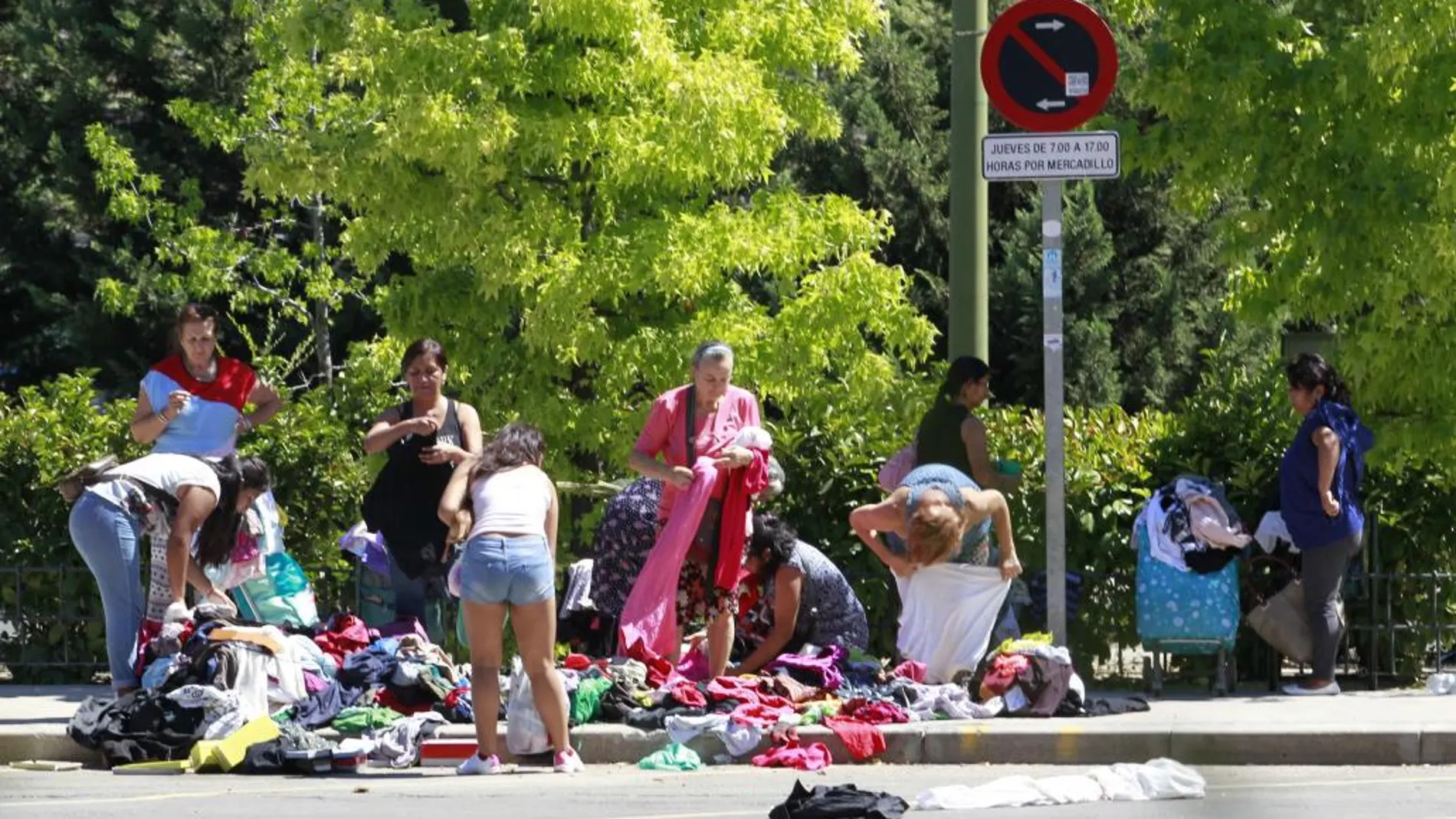 Gente buscando ropa y comida entre los restos de un mercadillo ambulante en Madrid.
