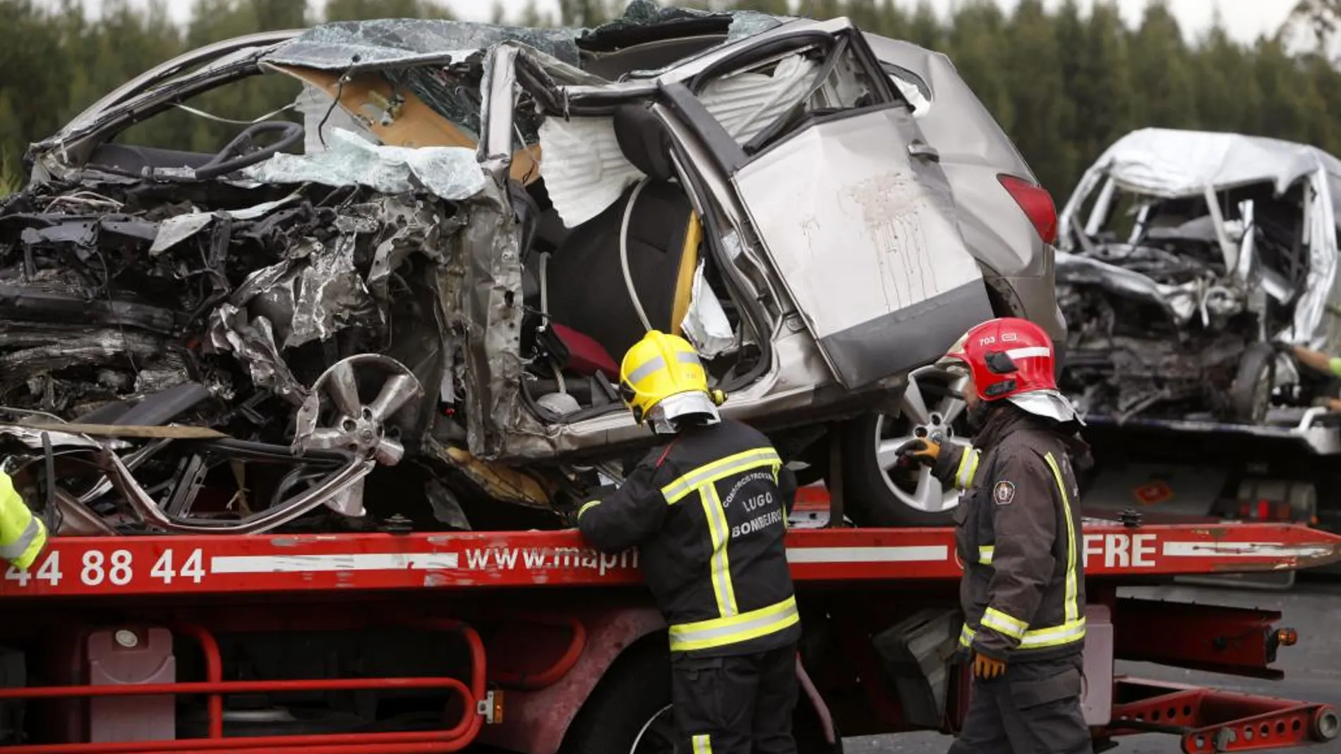 Bomberos de Lugo retiran los restos de los vehículos siniestrados en un accidente en la A-6 que comunica A Coruña con Guitiriz (Lugo), el sábado