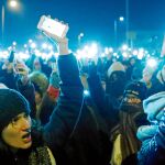 Cientos de manifestantes encienden sus teléfonos ayer en las inmediaciones de la televisión pública en Budapest / Reuters