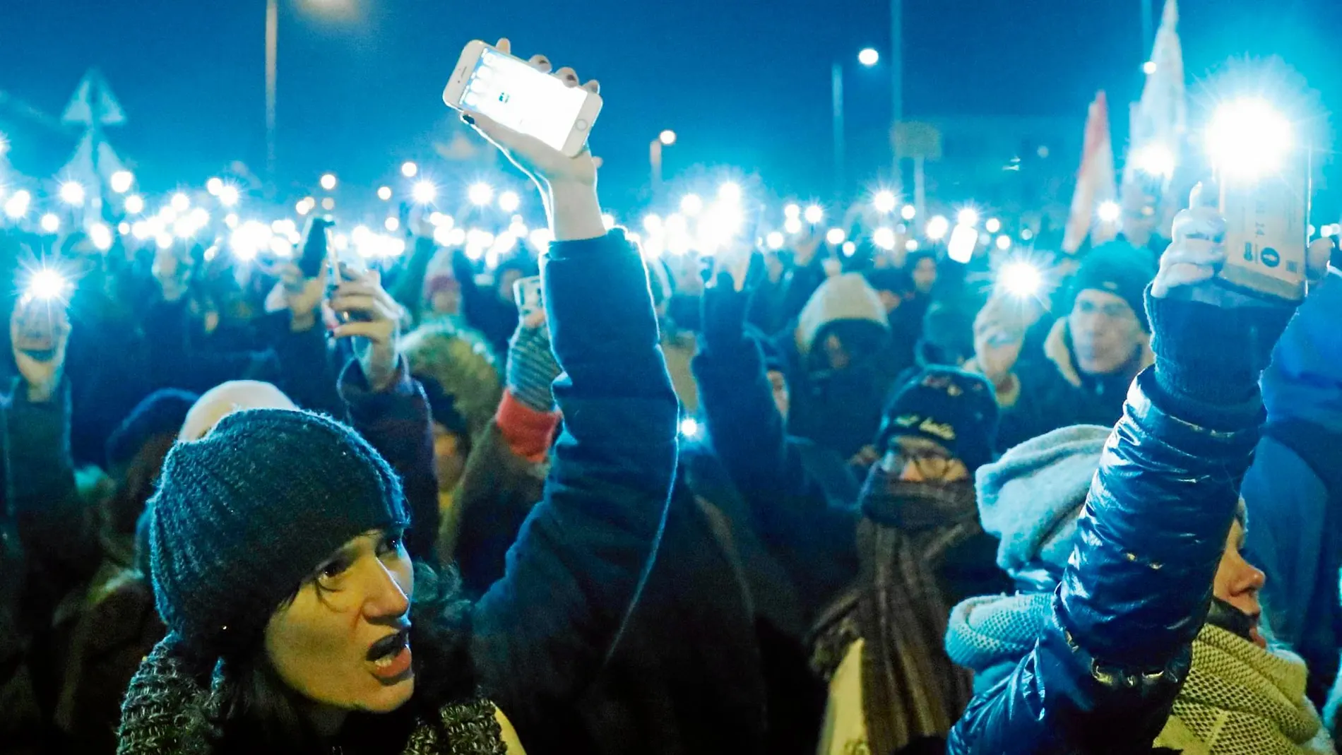 Cientos de manifestantes encienden sus teléfonos ayer en las inmediaciones de la televisión pública en Budapest / Reuters