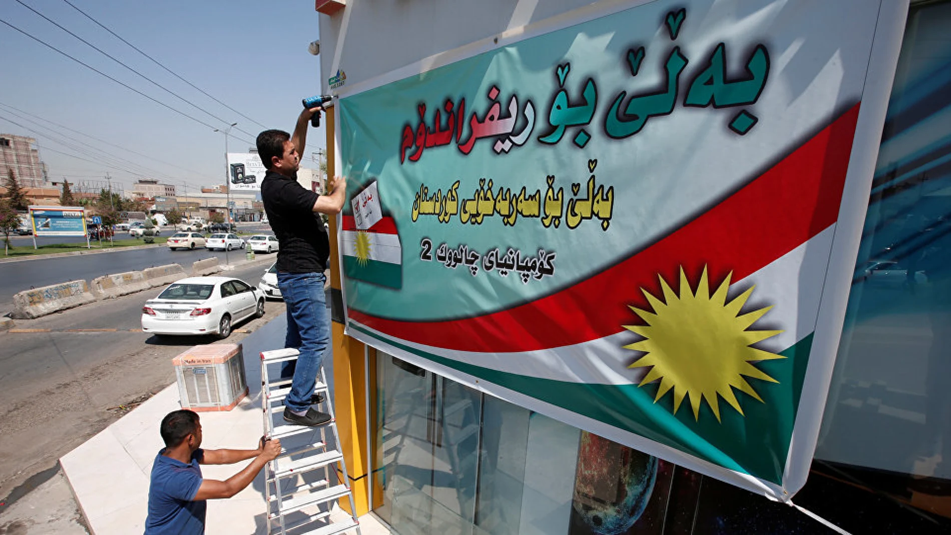 Los kurdos iraquíes colocan un cartel llamando a votar en el referéndum independentista