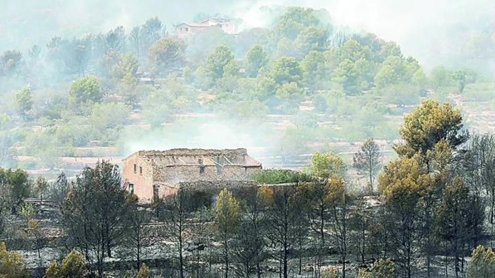 Imagen de una masía con el entorno quemado a causa del incendio en La Pobla de Montornès (Tarragona)