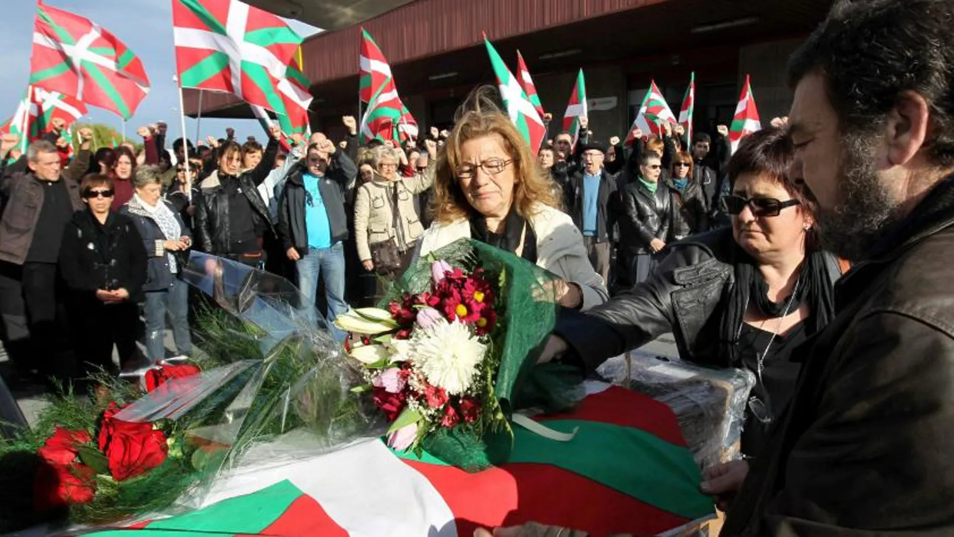Juanma y Begoña, hermanos del exdirigente de ETA "Thierry"colocan flores sobre el féretro durante el homenaje tributado a su llegada a la terminal de carga del aeropuerto de Bilbao