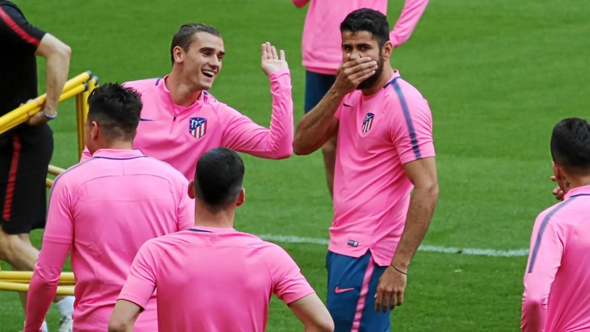 Griezmann da un manotazo a Diego Costa, que se tapa la boca durante el entrenamiento de ayer en el Metropolitano