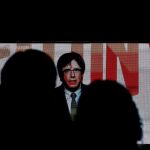 Varias personas, ante la pantalla desde la que Puigdemont ha pronunciado su discurso de cierre de campaña desde Bruselas