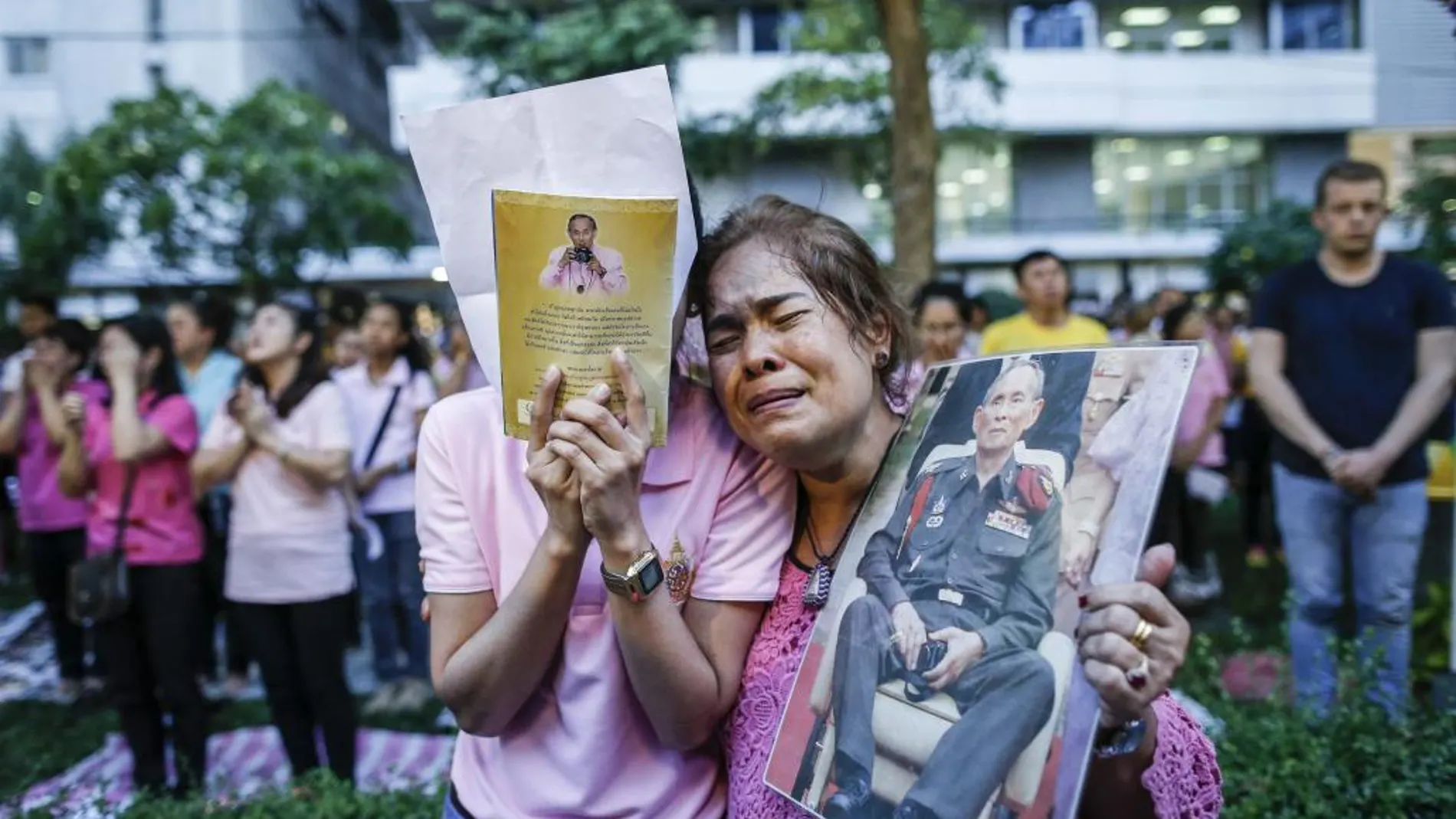 Dos mujeres tailandesas lloran tras conocer el fallecimiento del rey Bhumibol Adulyadej frente al hospital Siriraj, donde permanecía ingresado.