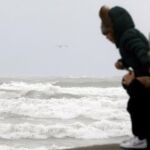 Tres personas observan el temporal marítimo en la playa de la Malvarrosa de Valencia, en una imagen de archivo