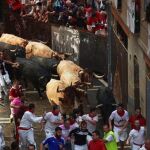 Corredores y toros a su paso por la plaza del Ayuntamiento, con toros de la ganadería de José Escolar, durante el segundo encierro de San Fermín en Pamplona. Rodrigo Jiménez/EFE