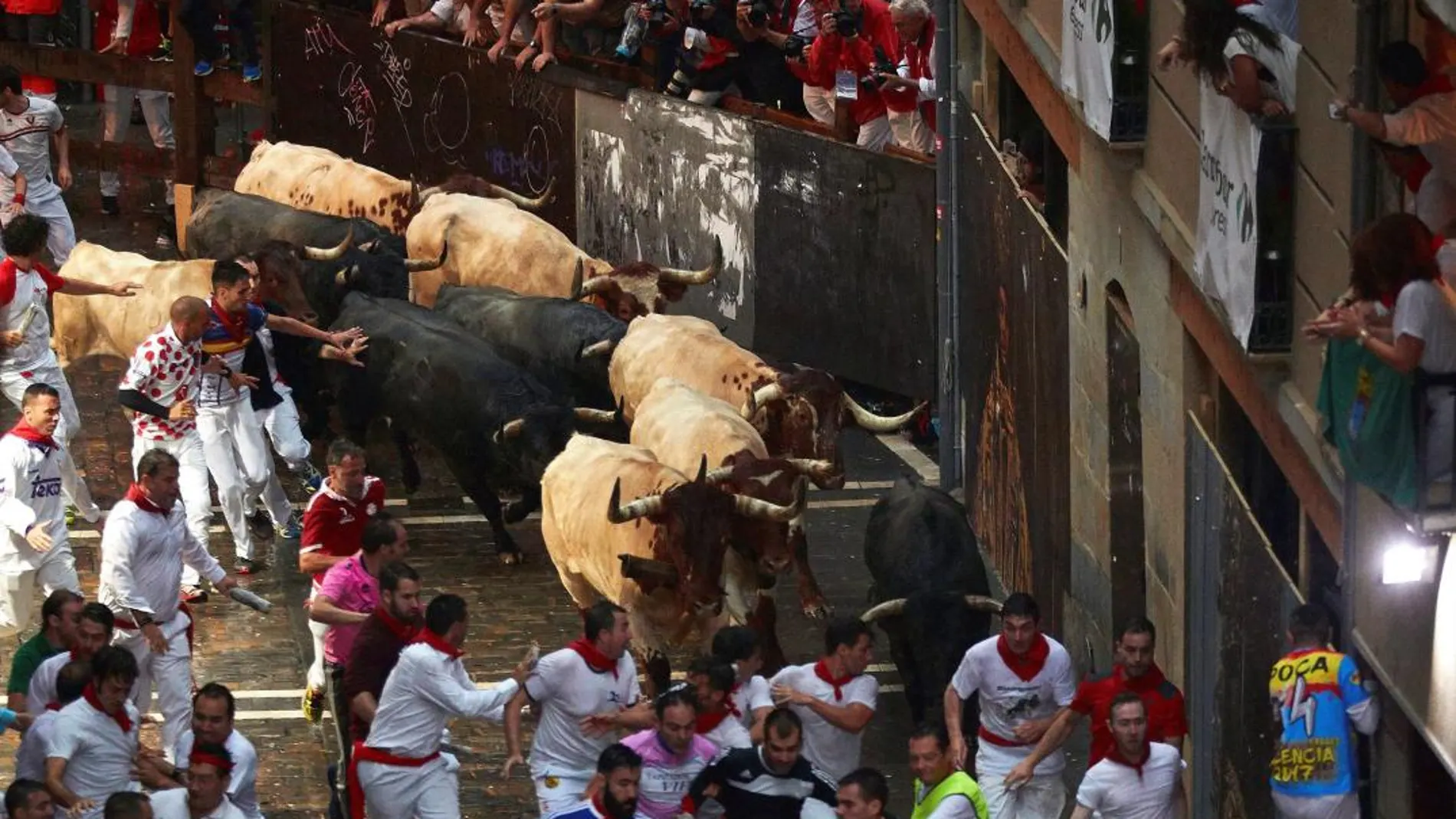 Corredores y toros a su paso por la plaza del Ayuntamiento, con toros de la ganadería de José Escolar, durante el segundo encierro de San Fermín en Pamplona. Rodrigo Jiménez/EFE