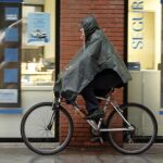 Un ciclista se proteje de la lluvia en Valencia