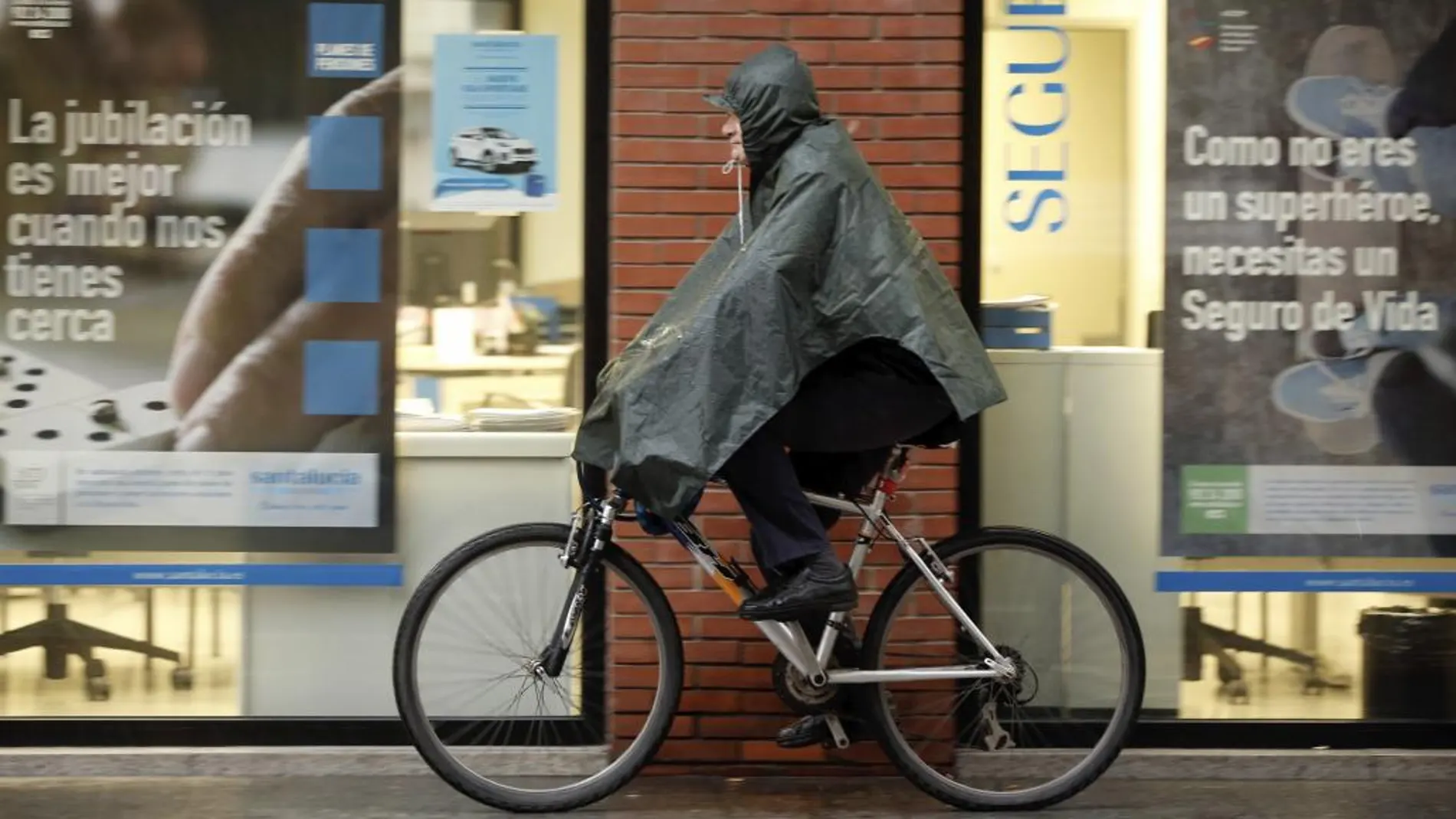 Un ciclista se proteje de la lluvia en Valencia