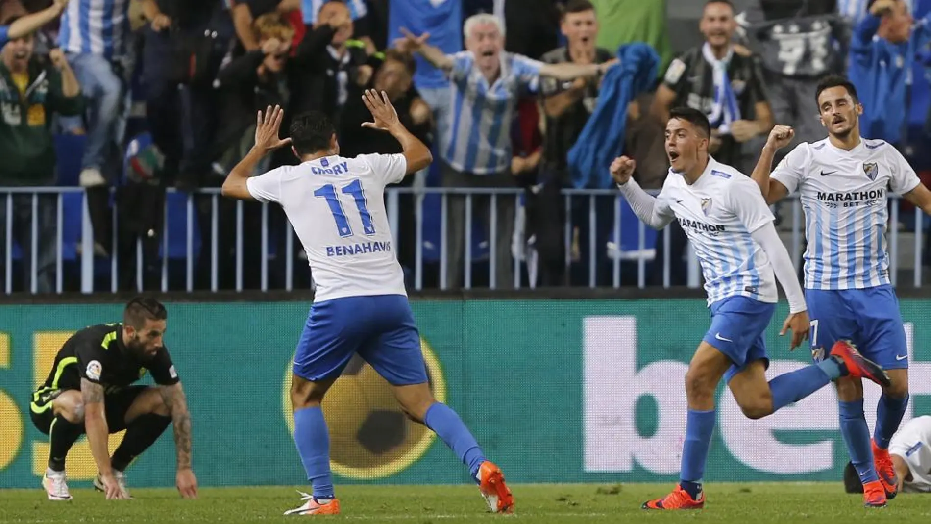 El centrocampista del Málaga Pablo Fornals (2d) celebra su gol, primero del equipo, junto a sus compañeros el defensa Juankar Pérez (d), y el centrocampista "Jony"Rodríguez, ante el defensa del Sporting Lillo (i)