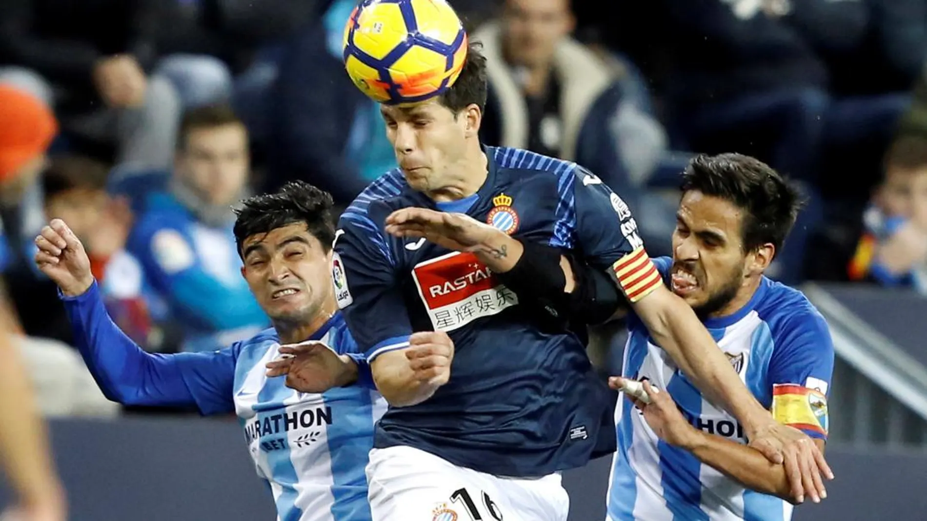 El centrocampista del RCD Espanyol Javi López (c) pelea un balón con los jugadores del Málaga CF, Chory Castro (i) y Recio